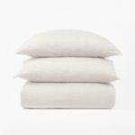 Amity home damara duvet cover in ivory folded with two matching shams stacked above showcasing its subtle texture