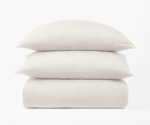 Amity home damara duvet cover in ivory folded with two matching shams stacked above showcasing its subtle texture