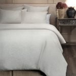 Amity home damara duvet cover in sea glass with a subtle linen like texture styled on a bed with matching pillow shams