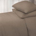 Amity home damara duvet cover in walnut styled on a bed with two stacked pillows showing soft linen texture against sheer curtains