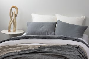 Amity home damara duvet cover in neutral grey linen styled on a bed with matching pillows and a textured throw