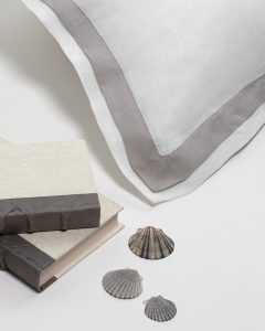 Amity home orfeo linen duvet cover   white and grey layered border with visible soft linen texture Styled with books and seashells