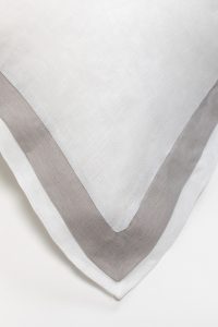 Amity home orfeo linen duvet cover   close up of folded white linen with a crisp grey border highlighting the fabric texture