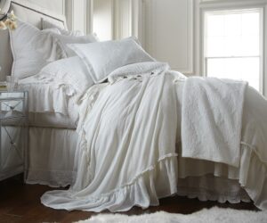 Amity home caprice duvet cover in white featuring soft ruffles styled on a luxurious bed with layered white pillows and a quilted throw