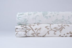 Amity home riva duvet cover   rolled natural linen duvet with brown scrolling floral pattern stacked with a blue patterned duvet