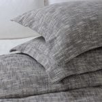 Amity home evol duvet cover and matching pillows in charcoal with a textured speckled weave styled on a bed