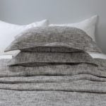 Amity home evol duvet cover and shams charcoal with a textured woven melange pattern styled on a bed