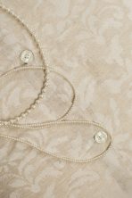 Amity home odette duvet cover   close up of light beige fabric with subtle woven jacquard floral pattern and mother of pearl buttons