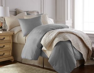 Amity home lia rayon velvet duvet cover   limestone grey velvet bedding draped on a luxurious bed with cream quilted layers