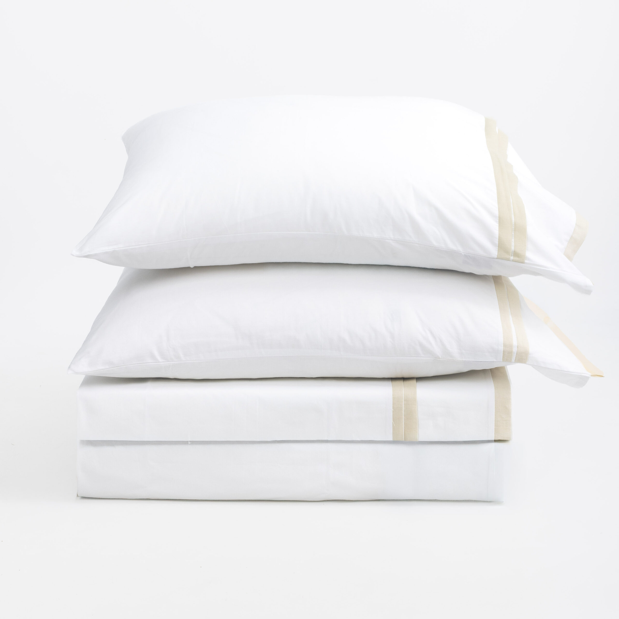 15bbc2 | Amity Home Stack of white pillows stacked on top of each other with beige seam tape against a plain white background conveying a clean bedding scene