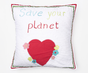 White decorative pillow with save your planet embroidered text a red heart and colorful flower accents