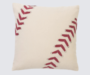 Beige decorative pillow with red baseballstitch style lacing along diagonal seams on cream fabric