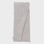 Light gray knitted throw blanket folded with a corner draped over the edge