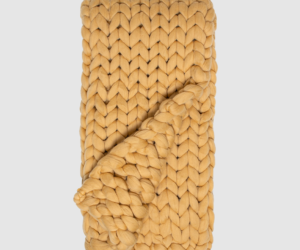 Mustard yellow chunky knit scarf folded with oversized interwoven stitches showing a looped end