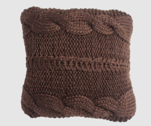 Brown knitted throw pillow with a prominent cable knit pattern on a light background