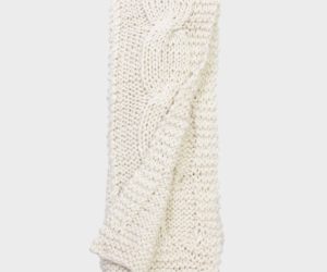 Cream chunky knit scarf folded with a cable pattern on a light background
