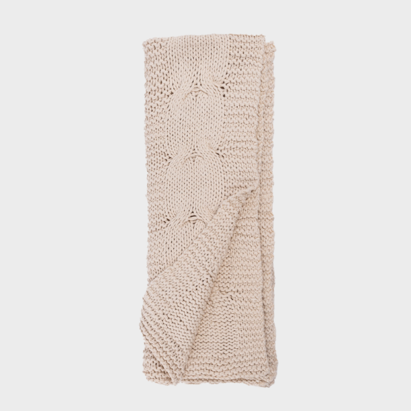Beige chunky knit scarf folded with a cable knit pattern and ribbed edges