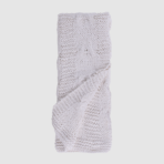 Cream knitted scarf folded featuring a cable pattern on a light background