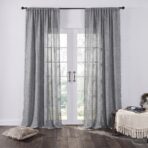 Tall white framed french doors with sheer gray curtains allowing light to filter in view of greenery outside