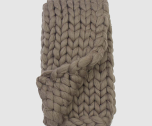 Thick beige chunky knit scarf folded with a knot in the center Intended for winter warmth and texture Or a knitted beige scarf with oversized yarn stitches tied in the middle