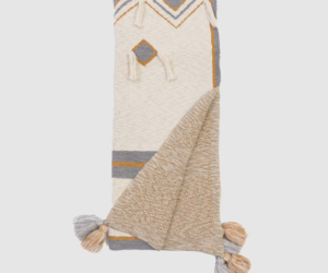 Cream woven throw blanket with gray and mustard geometric pattern and tasselled corners folded in two