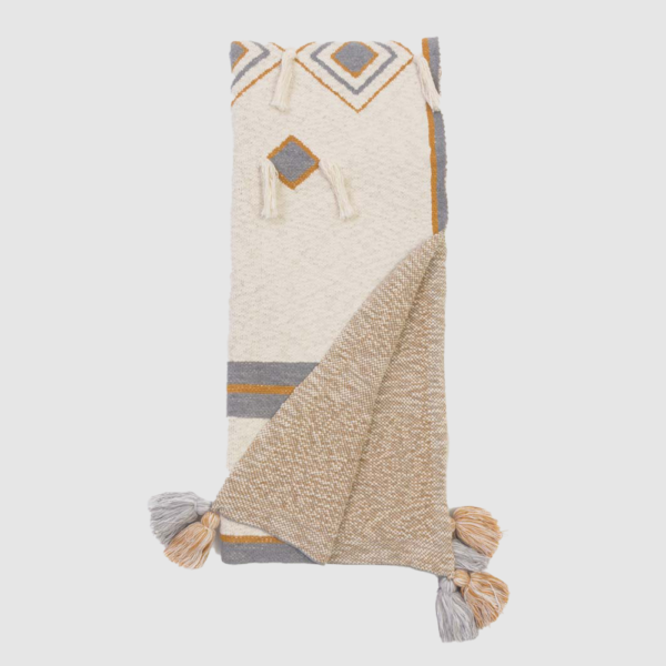 Cream woven throw blanket with gray and mustard geometric pattern and tasselled corners, folded in two