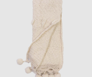 Cream knitted scarf with tassels and pom pom fringe along the edge