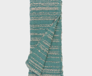 Teal woven textile folded with cream stripes and fringe along the edges likely a towel or throw blanket