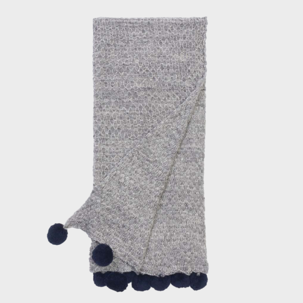 Grey knitted scarf with navy pom-poms along the ends, folded in half