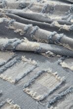 Close up of distressed blue denim fabric with white frayed edges and fringe detail