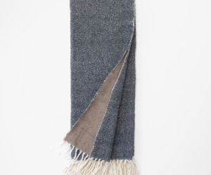 Dark blue denim scarf with a beige underside and white fringe folded flat on a white background