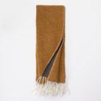 Brown woven scarf with white fringe laid flat one corner folded to show a gray underside