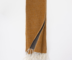 Brown woven scarf with white fringe laid flat one corner folded to show a gray underside