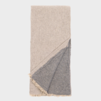 Beige folded throw blanket with a gray fringed underside showing on the corner edge