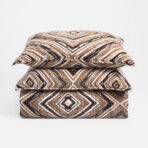 Stack of patterned brown black and white geometric pillows on a white background