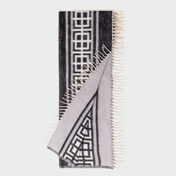 Geometric black-and-white scarf with fringed edges, folded to display the pattern.