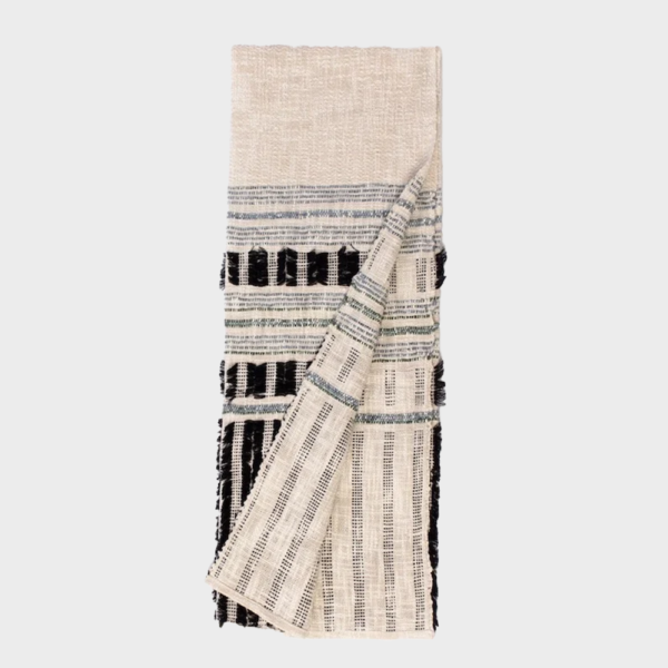 Beige woven throw blanket with black and navy stripes, folded with a corner pulled back.