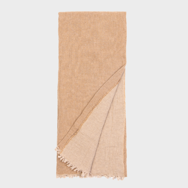 Beige woven scarf with fringed edges folded at the corner on a light background
