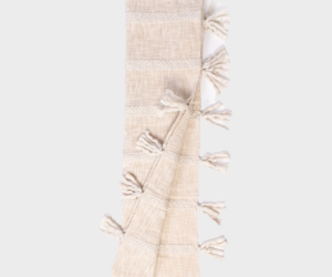 Beige woven scarf with tassels along the edges folded in a narrow strip