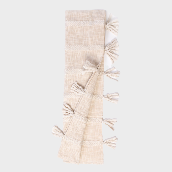 Beige woven scarf with tassels along the edges, folded in a narrow strip.