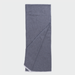 Blue knit scarf folded with fringe at one end laid flat against a light background