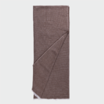 Brown woven scarf folded lengthwise with a diagonal overlap and fringed edge at the bottom corner on a light background