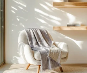 Armchair with a gray striped throw in a sunlit corner wooden shelves casting shadows on the wall behind