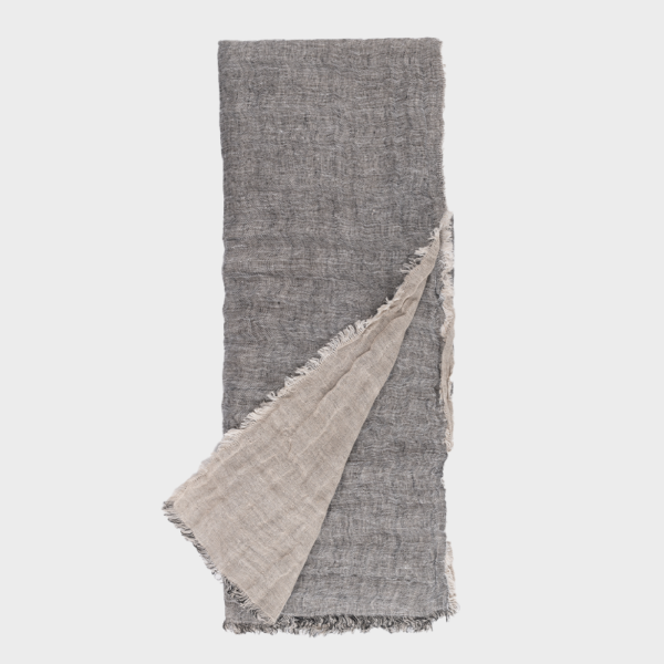 Gray woven scarf with a beige underside, folded diagonally across the image, fringed edges visible.