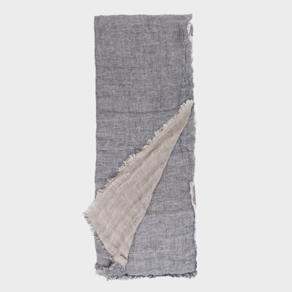 Blue-gray linen scarf with frayed edges, partly folded to reveal a beige underside.