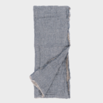 Blue gray linen scarf with frayed edges laid flat with one corner folded over