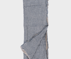 Blue gray linen scarf with frayed edges laid flat with one corner folded over