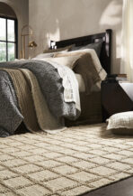 Bedroom scene with a dark wood bed beige quilted bedding and a brass arc lamp by a window