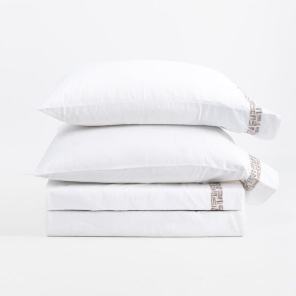 Stack of white pillows stacked in a neat pile, featuring a brown woven edge pattern on one side