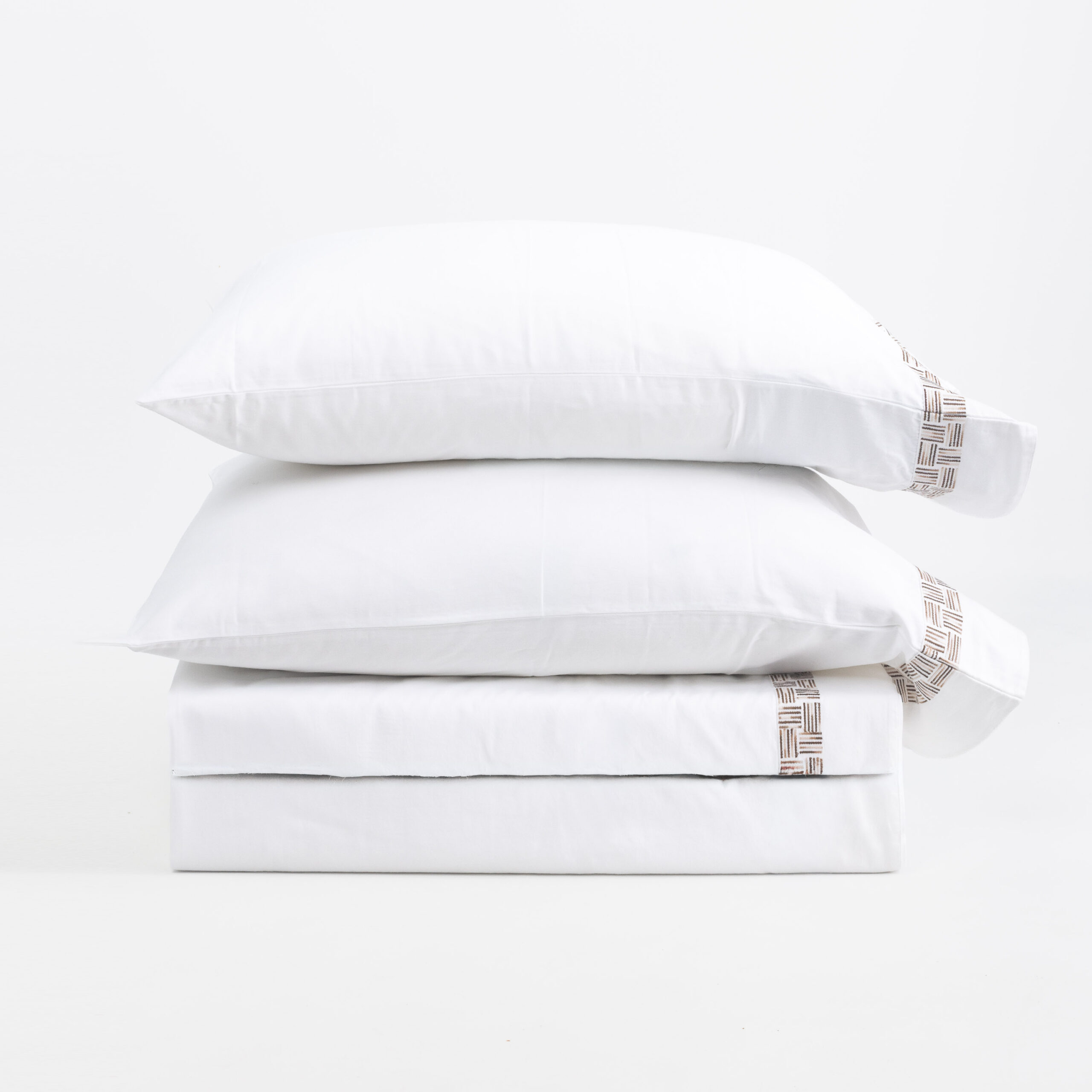 17217s1ah Low3 | Amity Home Stack of white pillows stacked in a neat pile featuring a brown woven edge pattern on one side
